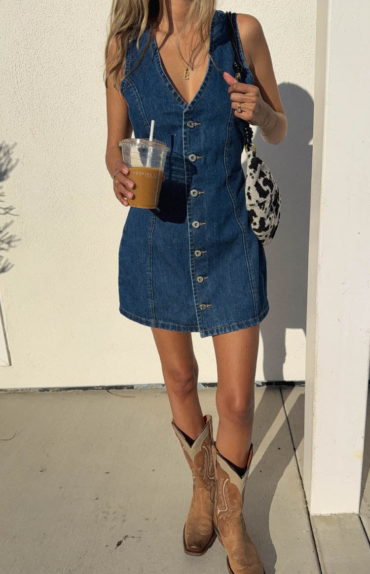 Full length view of a dark wash denim mini dress with a V-neckline and a full button-front closure