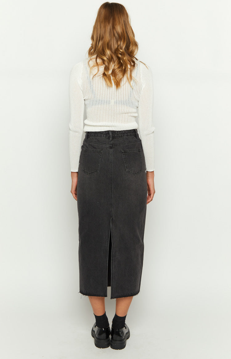 Rear view of a washed black denim midi skirt with back pockets, a long back slit, and raw hem