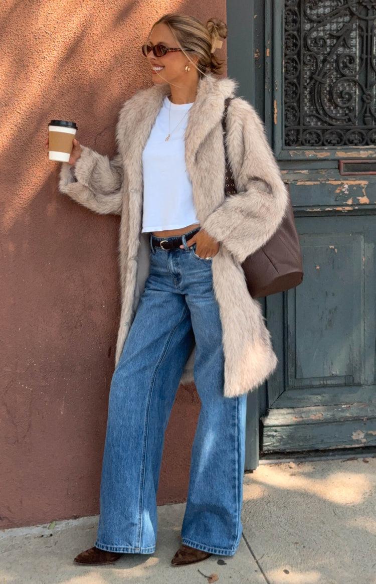 Full length view of a sand faux fur maxi coat with a wide lapel collar and long sleeves, worn open
