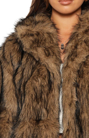 Close-up of the chocolate faux fur jacket showing the shaggy brown and black fur texture and wide lapel