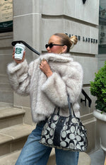 Side view of a sand faux fur jacket with a wide collar and plush texture