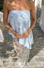 Close-up of the light blue strapless satin top showing its flowy asymmetric hem and soft drape