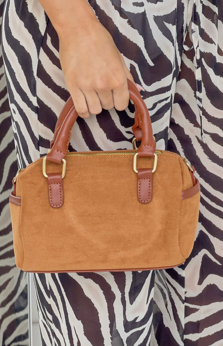 Close-up of the brown suede shoulder bag, showing the brown leather top handles and gold hardware