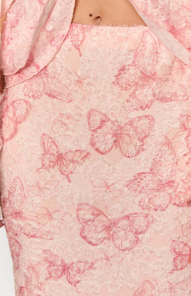 Detail shot of the pink maxi skirt fabric with a textured lace overlay and dark pink butterfly pattern