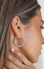 Close-up side view of a large silver hoop earring with a continuous row of sparkling diamante stones