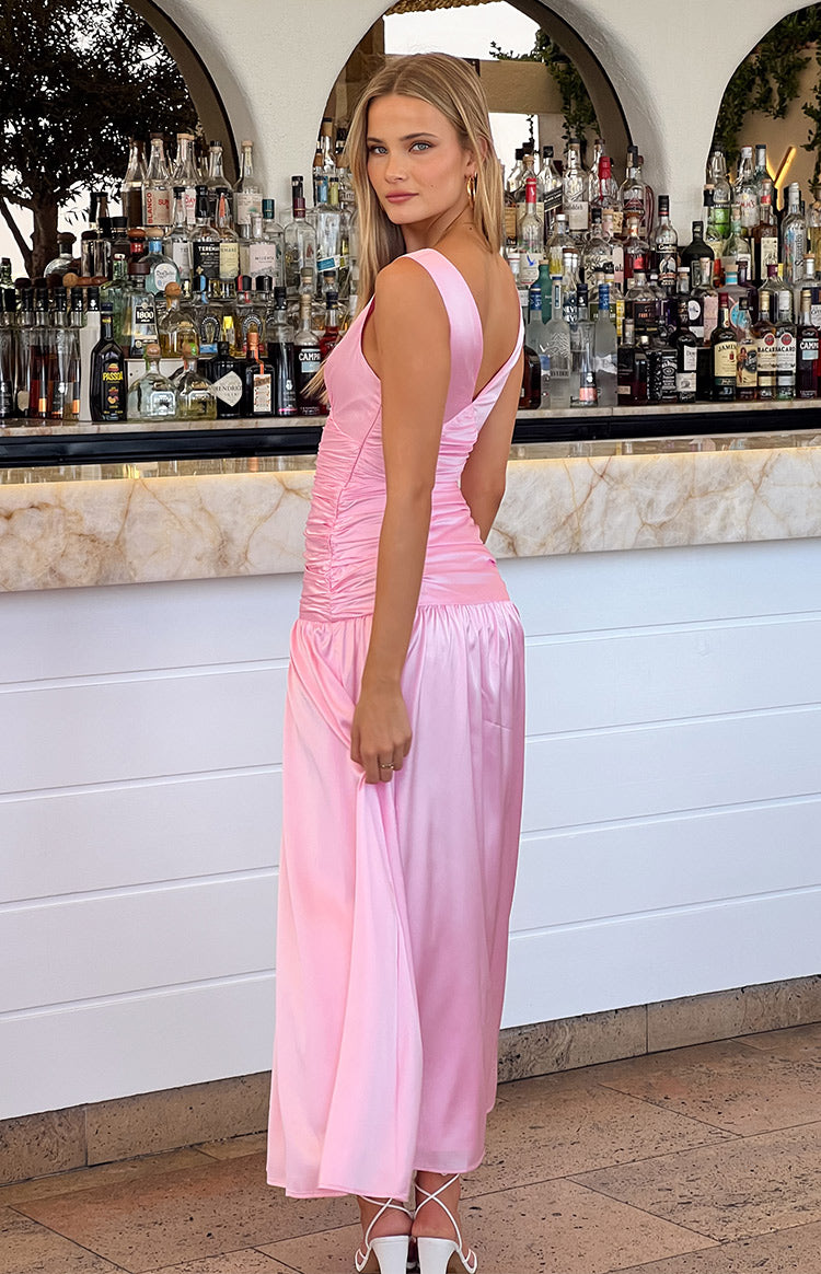 Side view of a pink gathered maxi dress with a V-neckline and flowing skirt