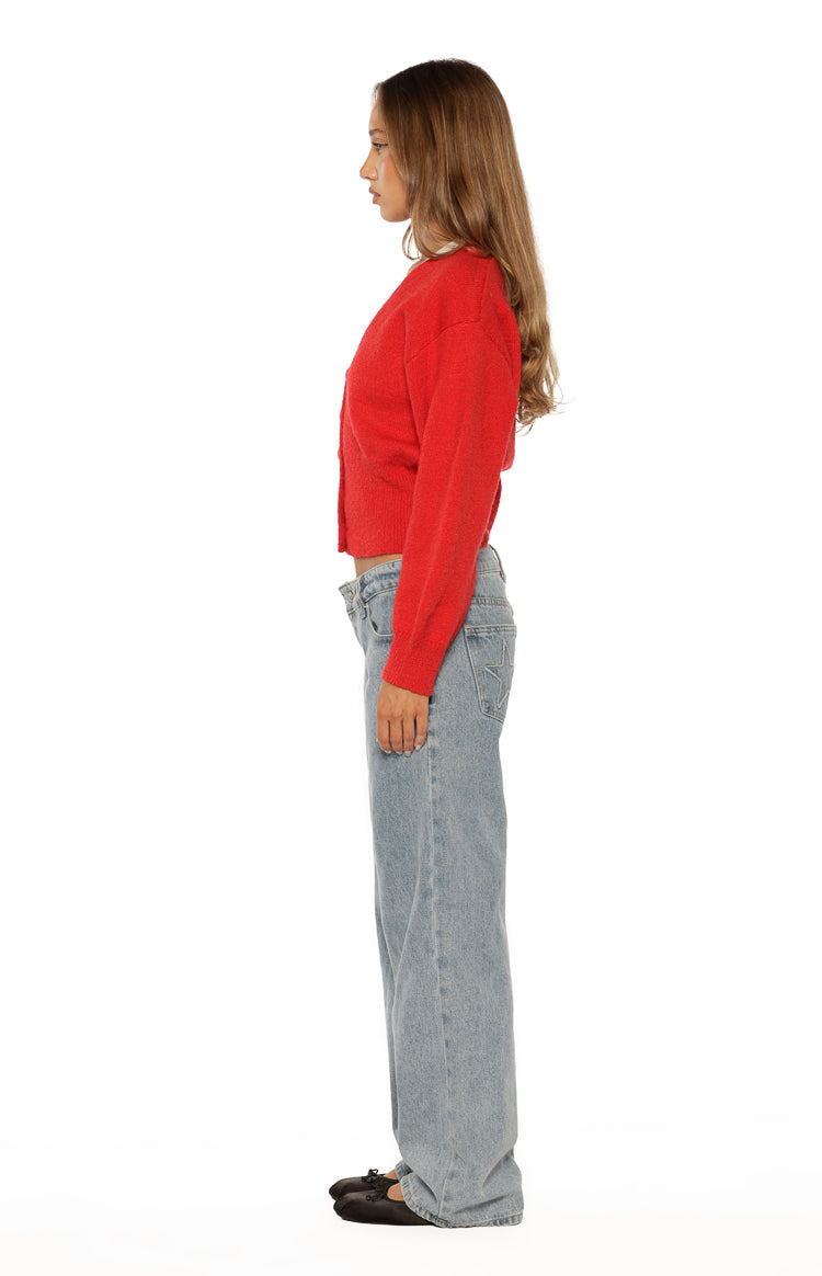Side view of a red knit oversized cardigan with long sleeves and a cropped hem