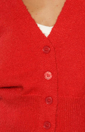 Close-up of the red knit cardigan's fuzzy texture, V-neckline, and front button placket with four red buttons