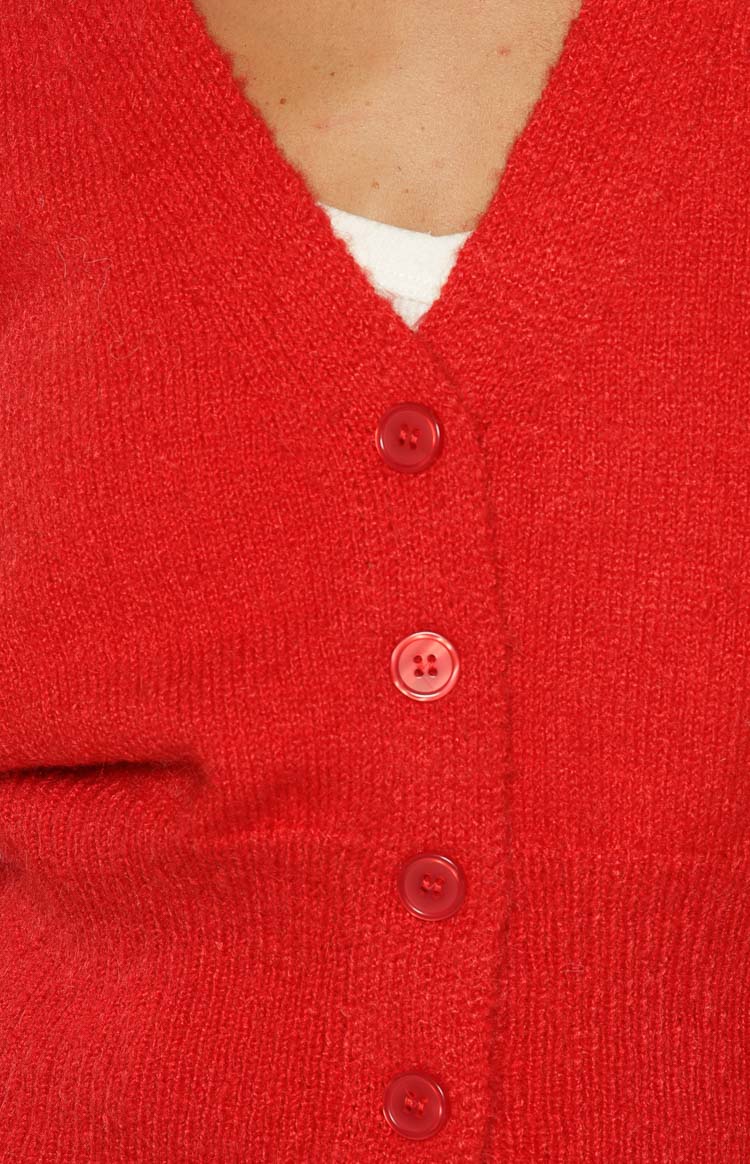 Close-up of the red knit cardigan's fuzzy texture, V-neckline, and front button placket with four red buttons