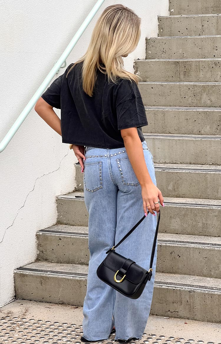 Rear view of light wash denim low rise jeans with studded detail along the waistband and pockets