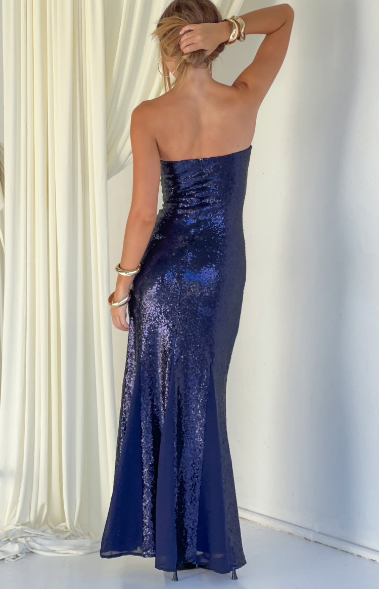 Rear view of a navy sequin strapless maxi dress with a fitted back and a flared hem with plain panels