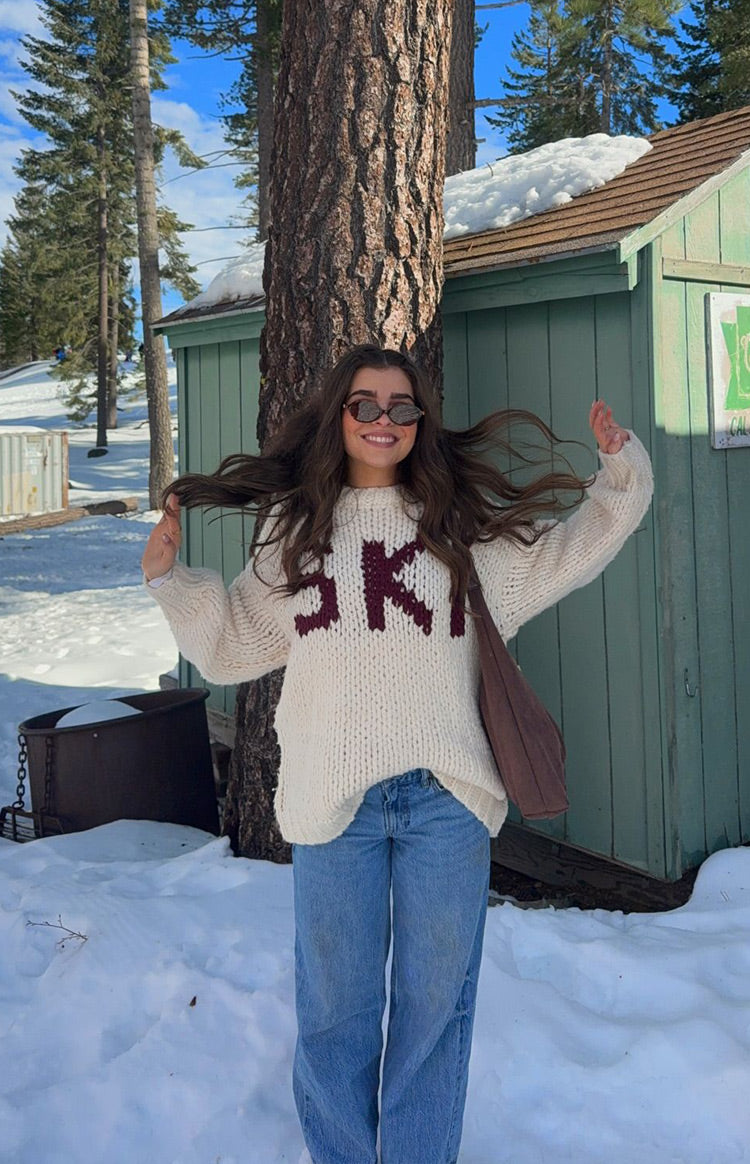 Front view of a cream chunky knit sweater with 'SKI' jacquard lettering on the chest