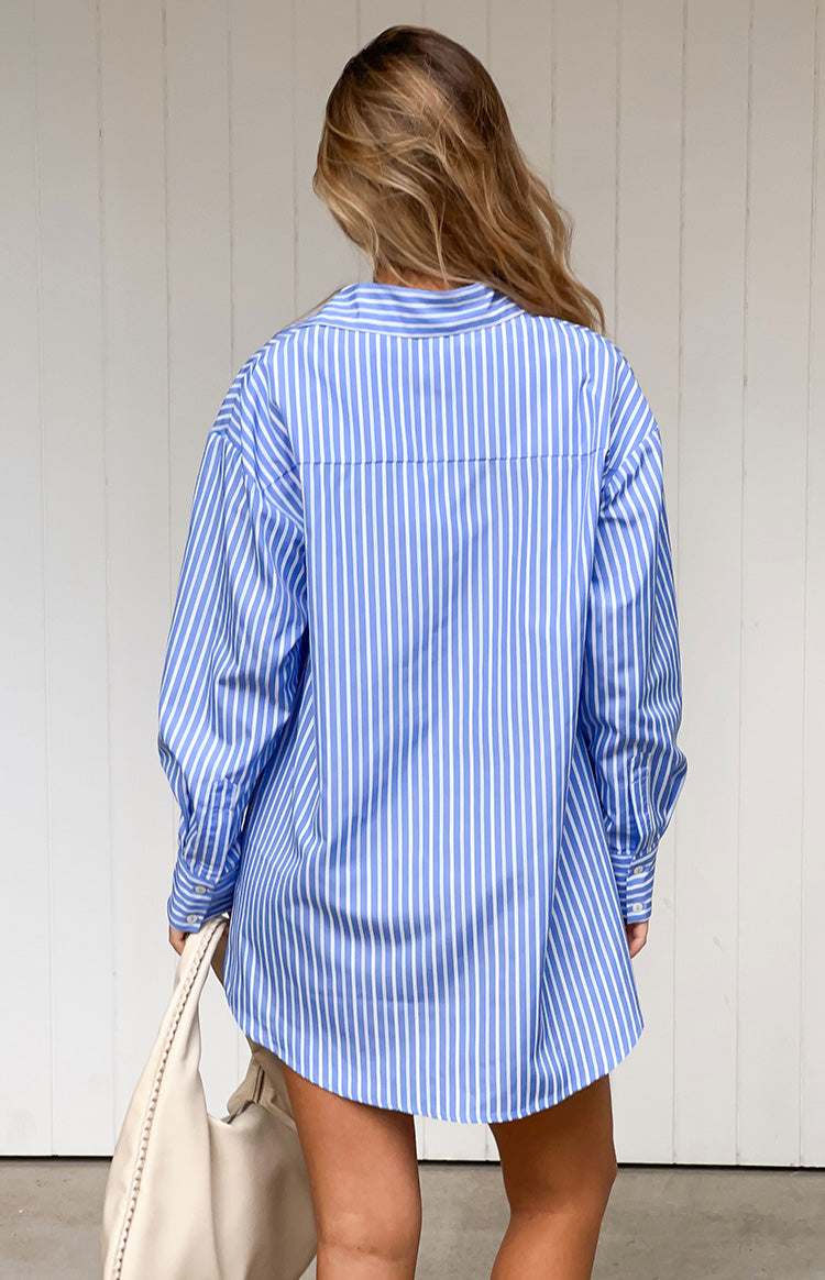 Rear view of the blue and white pinstripe shirt dress with a relaxed fit, long cuffed sleeves, and a curved hem