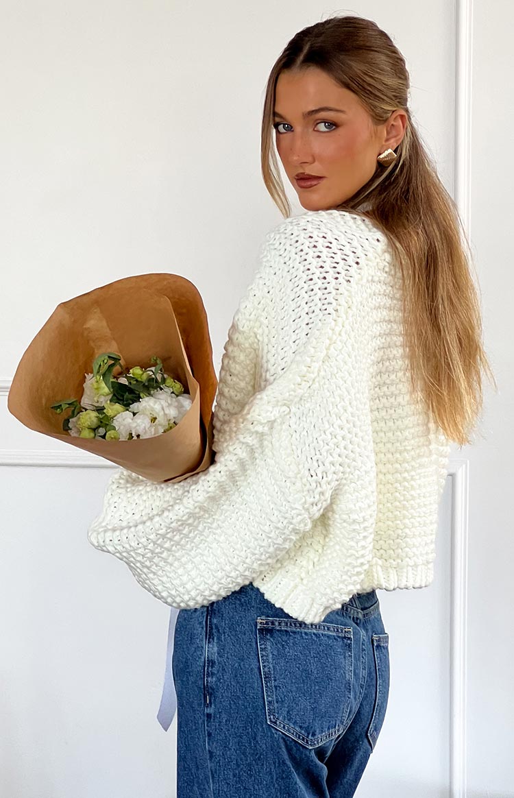 Rear view of a white chunky knit cardigan with wide sleeves and a ribbed hem