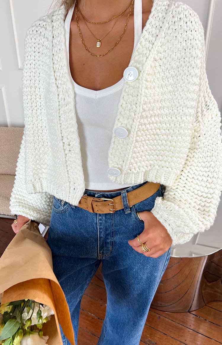 Close-up of the chunky knit texture and large white buttons on a cropped white cardigan