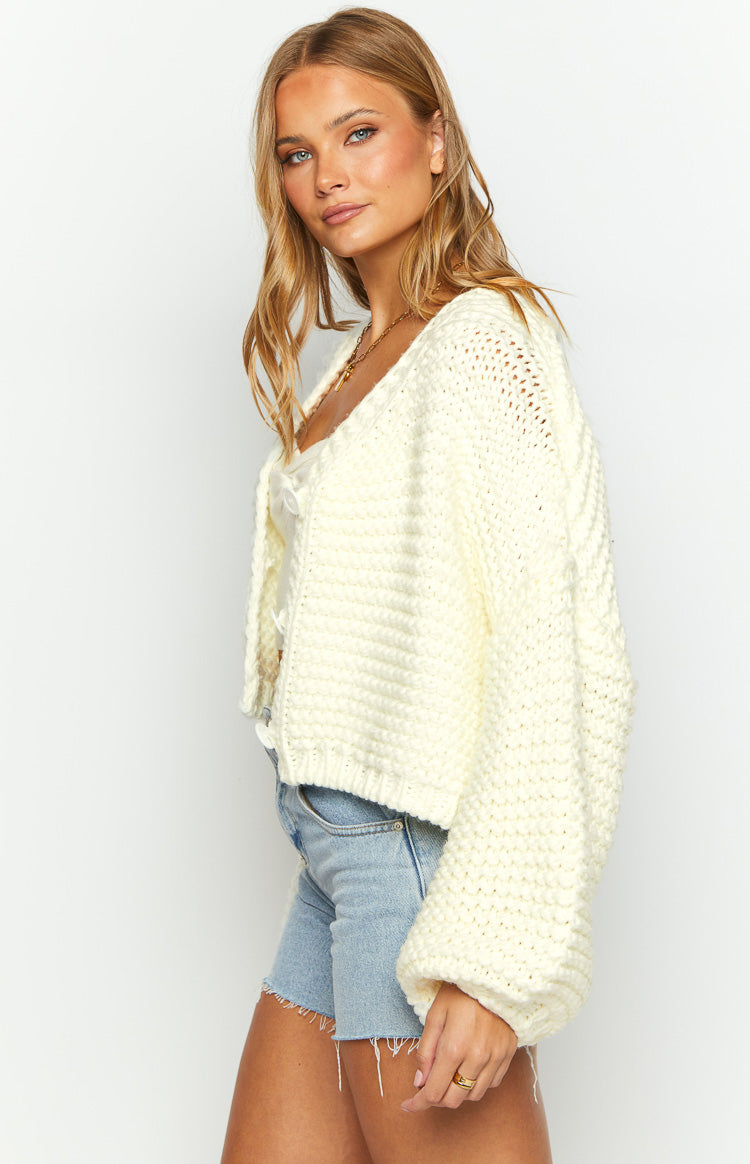 Side view of a white chunky knit cardigan with relaxed balloon sleeves and ribbed cuffs