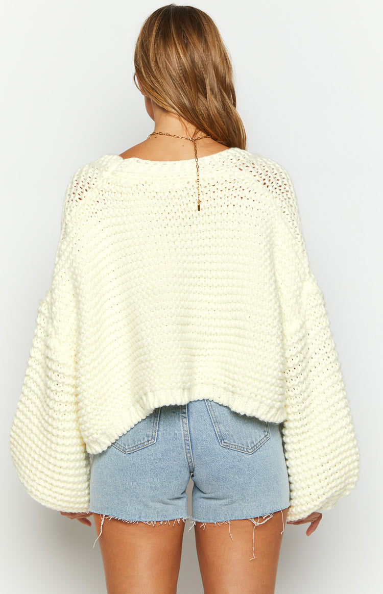Rear view of an off-white chunky knit cardigan with a wide boat neck and voluminous balloon sleeves