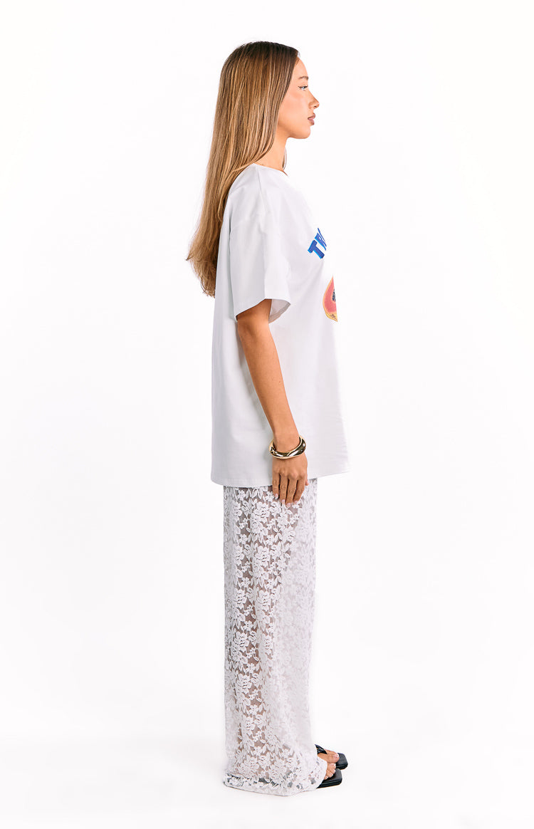 Side view of white wide-leg lace pants with a sheer floral pattern