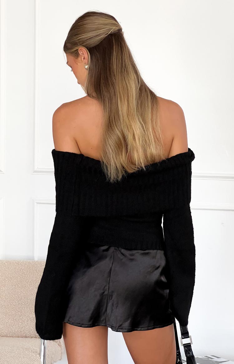 Rear view of a black off-shoulder sweater with a wide ribbed fold-over neckline and fitted waist