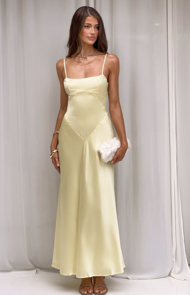 Pale yellow satin bias-cut maxi dress with a straight neckline, thin spaghetti straps, and V-seam detail