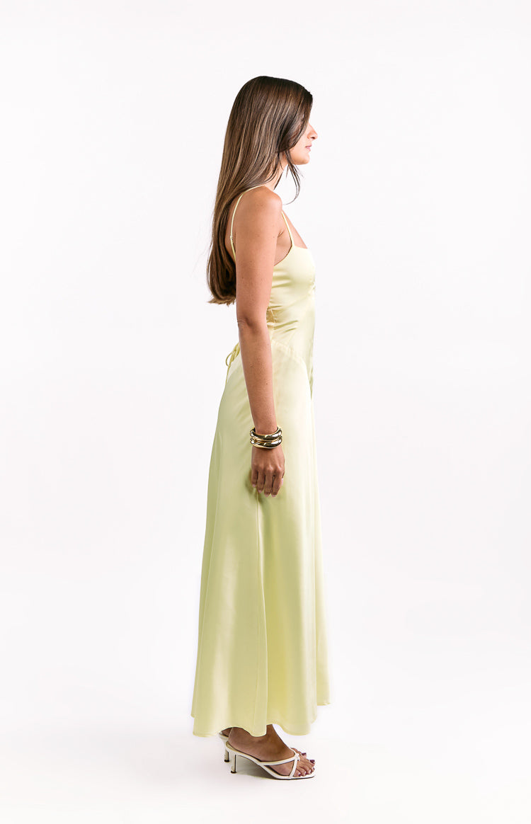 Side view of a yellow maxi dress with thin spaghetti straps and a flowing silhouette, showing the lace-up detail at the side waist