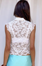 Rear view of a white floral lace top with a high neck, cap sleeves, and scalloped trim on sleeves and hem