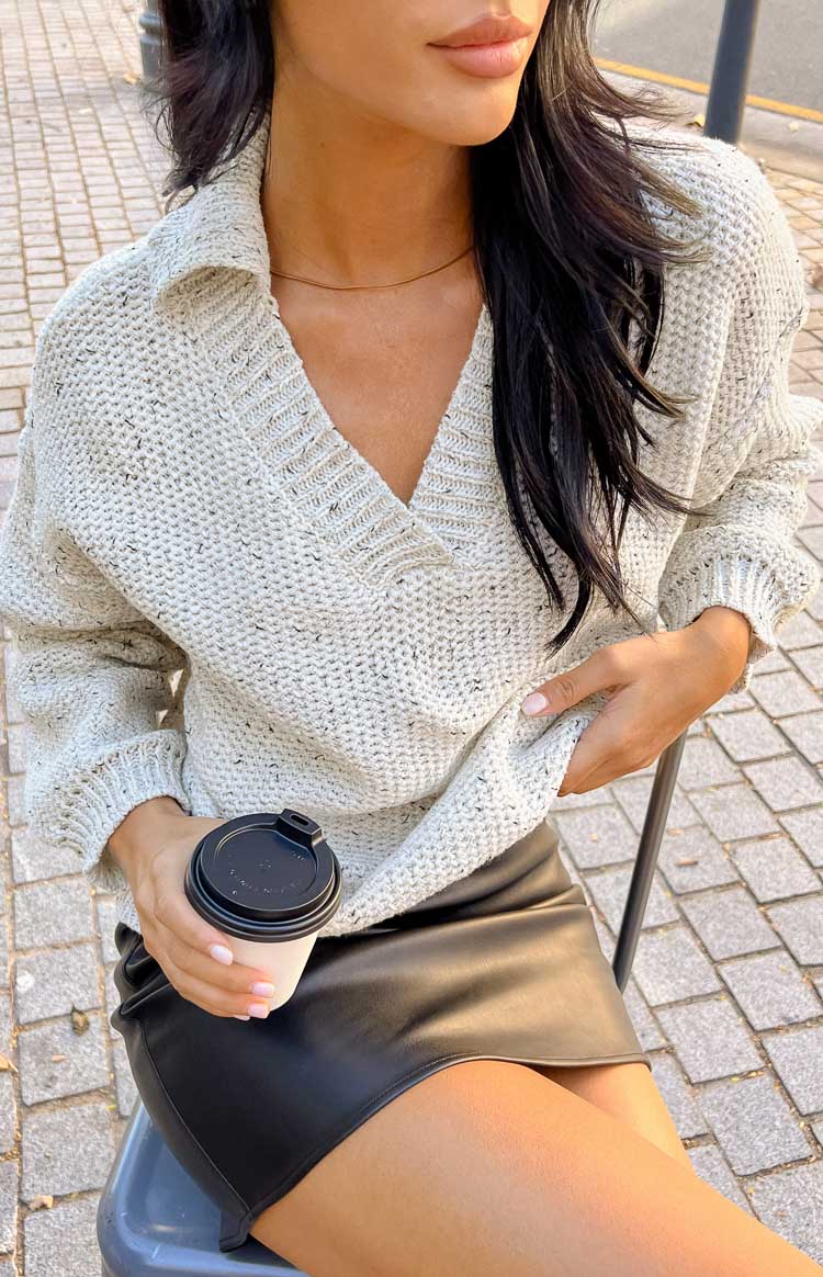 Close-up of the speckled light grey knit sweater with a V-neck and ribbed collar