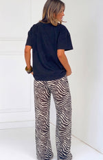 Rear-side view of black and white sheer zebra print wide-leg pants with a relaxed, flowy fit