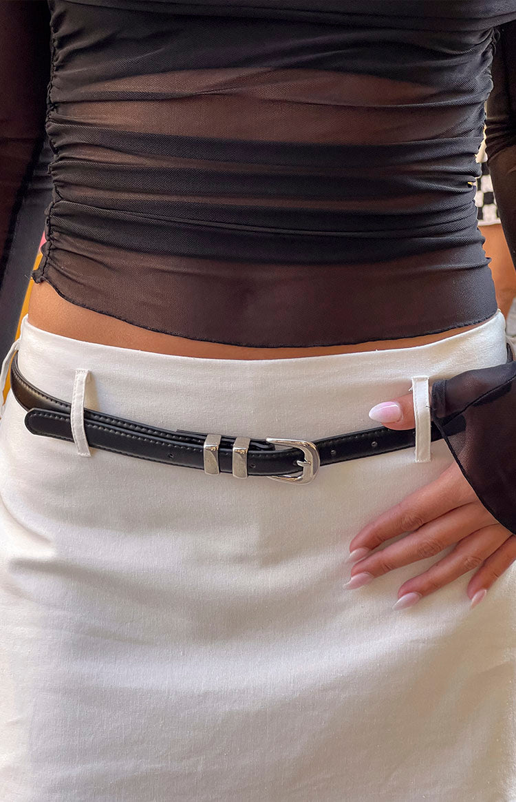 Close-up of a thin black PU belt with a silver buckle and two silver keeper loops