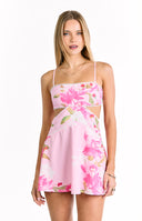 A sleeveless light pink floral mini-dress with a cut-out waist thin spaghetti straps and a decorative white pom-pom trim along the neckline and skirt. Our dress is suitable for a summer party or vacation.