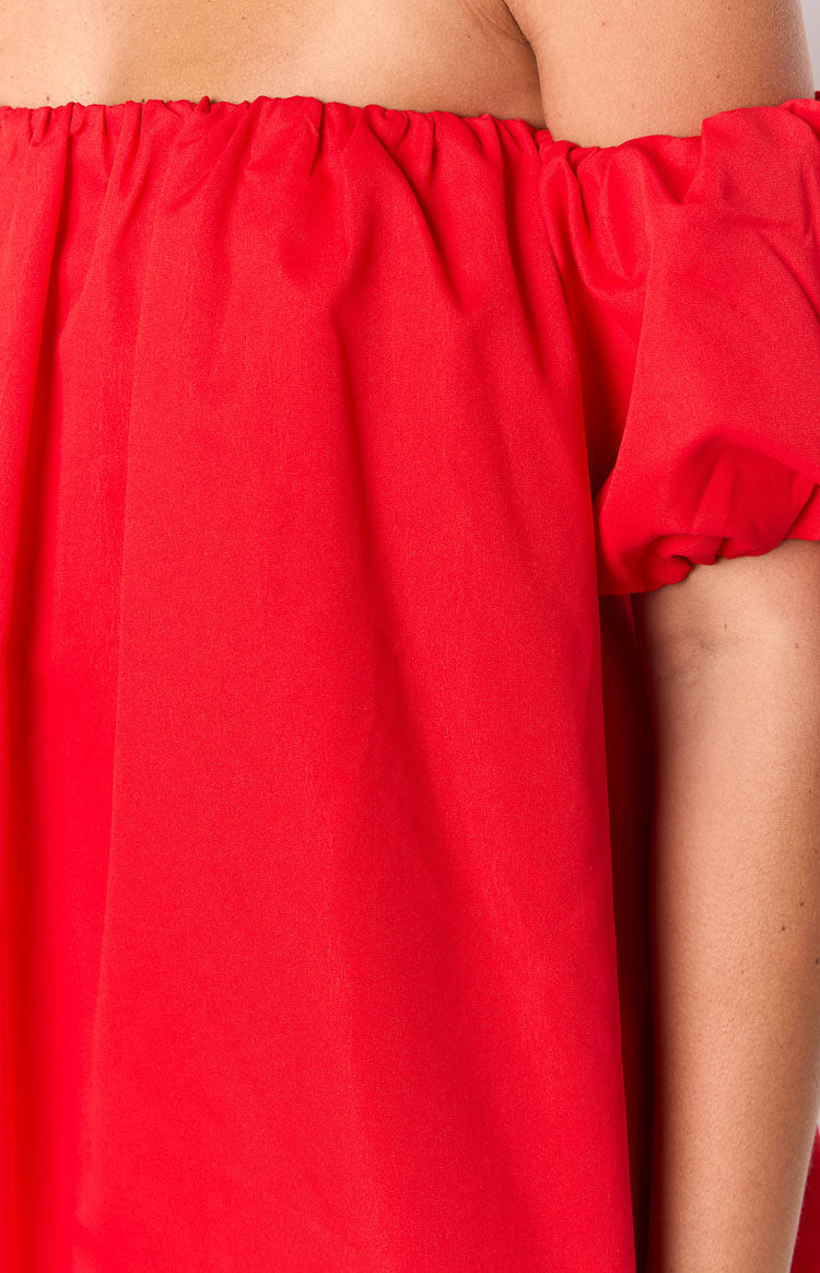 Close-up of the ruched elasticated off-shoulder neckline and short puff sleeve on a red mini dress