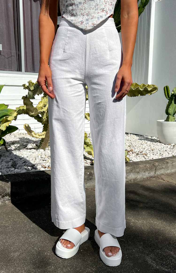 White high-waisted linen pants with a relaxed wide-leg fit and subtle front pleats