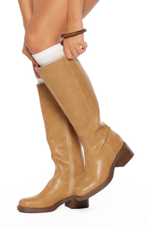 Close-up of the top opening of camel mid-length boots showing the side zipper and white stitching