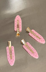 Four pink polka dot hair clips showing the gold-toned metal clip mechanism on the underside