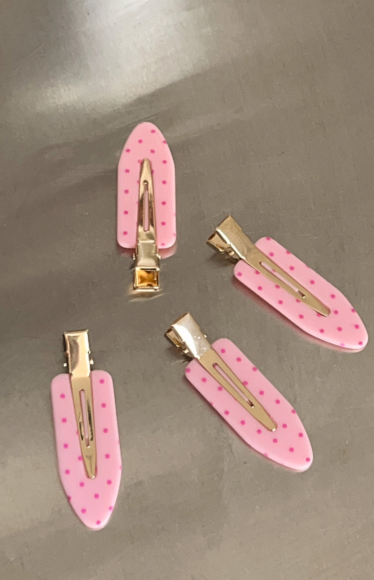 Four pink polka dot hair clips showing the gold-toned metal clip mechanism on the underside