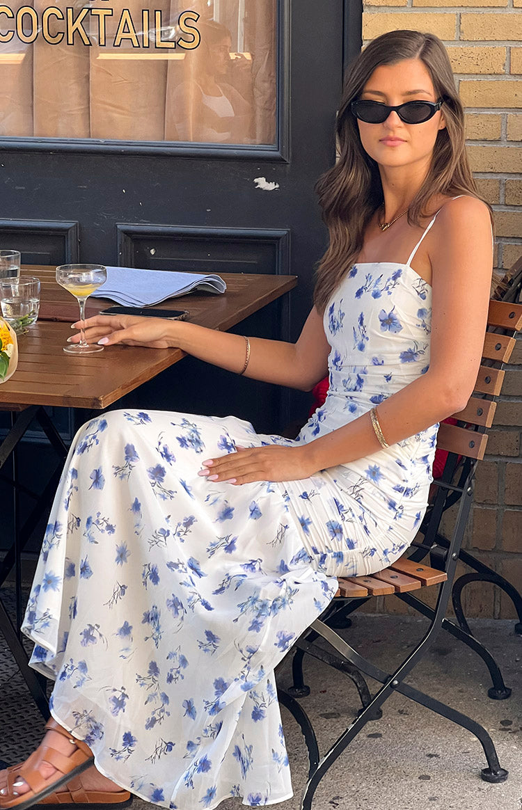 Side view of a white maxi dress with blue floral print, showing the square neckline and ruched side detail