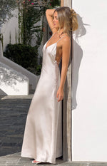 Side view of a cream satin maxi dress with a deep V-neck, thin spaghetti straps, and open back with criss-cross detail