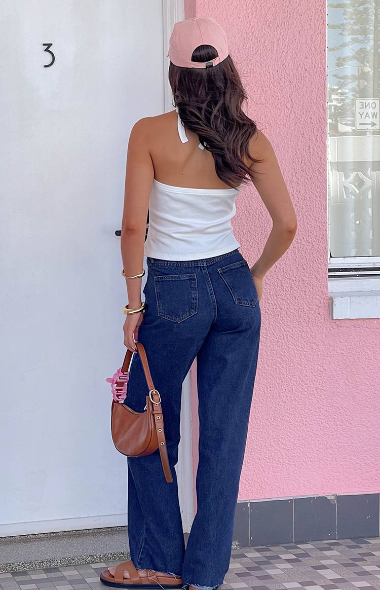 Rear view of dark blue straight leg jeans with back pockets and a raw hem