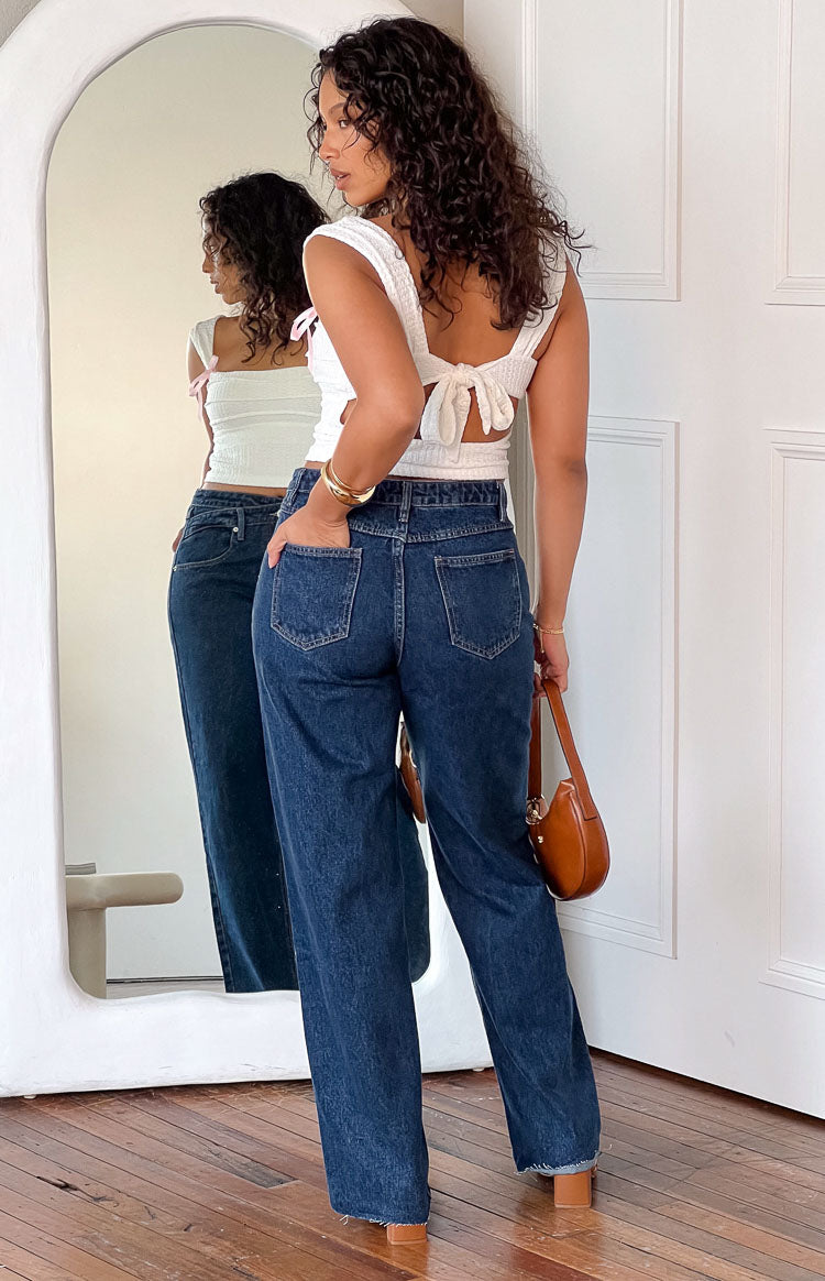 Rear view of dark blue straight leg jeans with back pockets and a raw hem