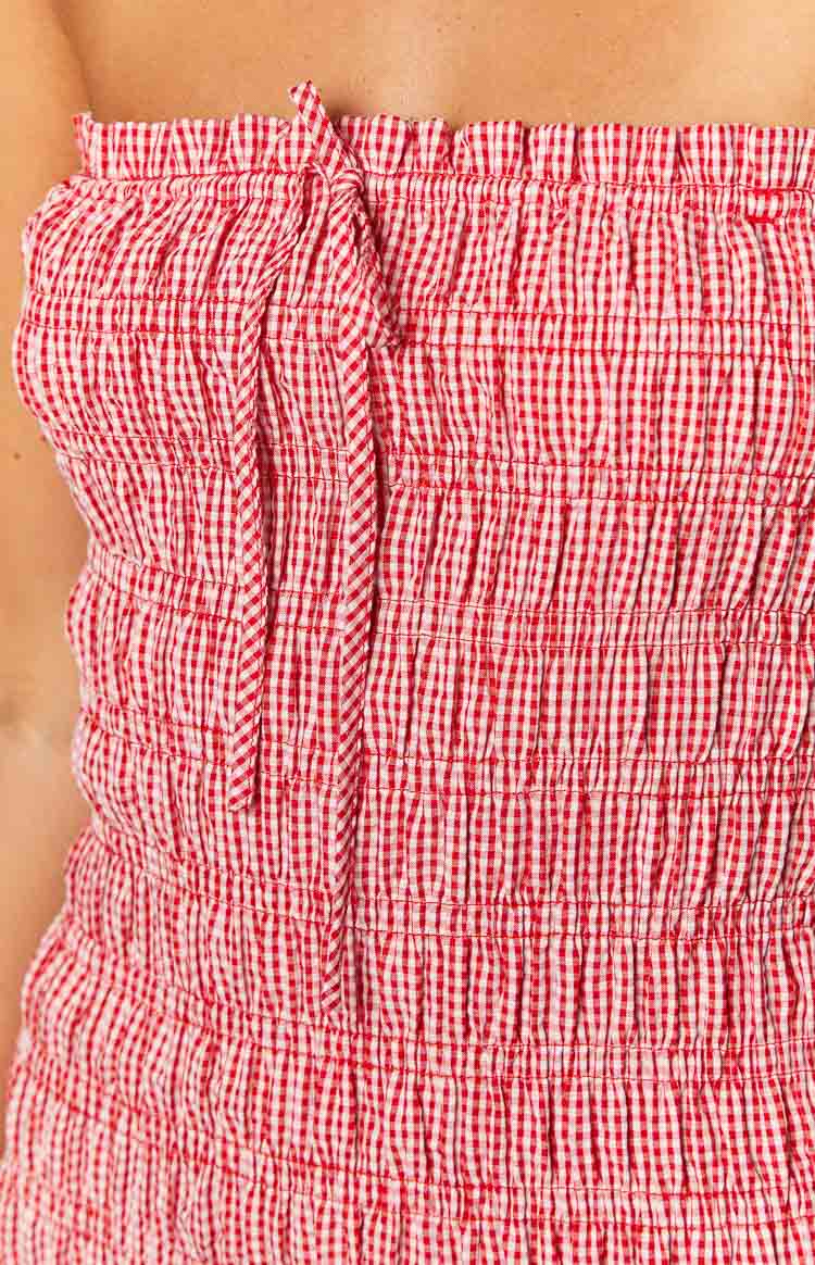Close-up of the red and white gingham shirred fabric with a tie detail on the strapless mini dress