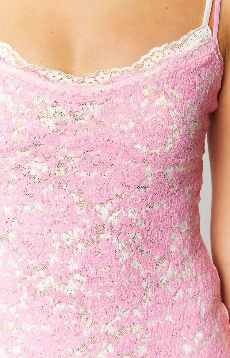 Close-up of the pink lace fabric with white floral pattern and white scalloped trim on the mini dress neckline