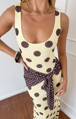 Yellow polka dot maxi dress with a scoop neck and contrasting brown polka dot fabric tied at the waist