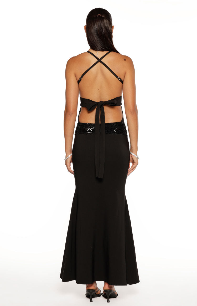 Rear view of a black maxi dress showing criss-cross back straps, tie-back closure, sequin waist detail, and flared hem