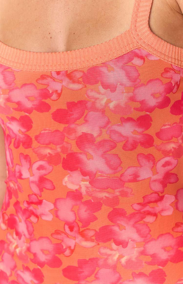 Close-up of the orange and pink watercolour floral pattern on the maxi dress, with a ribbed orange knit trim at the neckline