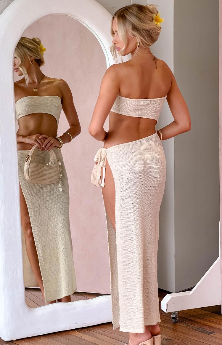 Rear view of a beige knitted maxi dress with a strapless bandeau top and a high side slit with tie detail