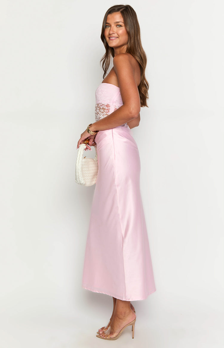 Side view of a pink strapless maxi dress with a lace bodice and flowing satin skirt