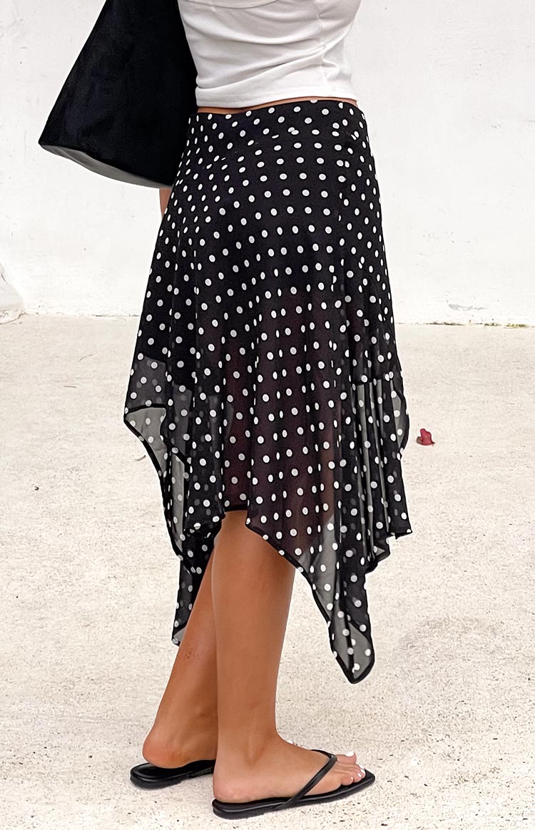 Side view of a black polka dot hanky hem midi skirt showing the sheer fabric and pointed hemline
