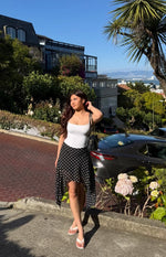 Black polka dot midi skirt with a flowy hanky hem showing the varied length