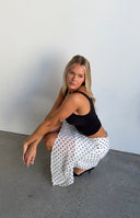 White polka dot midi skirt with a flowy hanky hem and a high leg slit