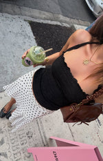 Overhead view of a white polka dot hanky hem midi skirt with a flowy drape